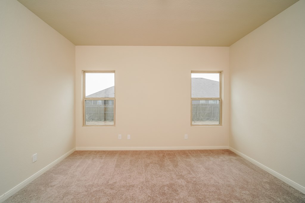 an empty room with a carpeted floor and two windows