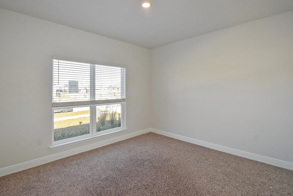 an empty living room with a window and carpet