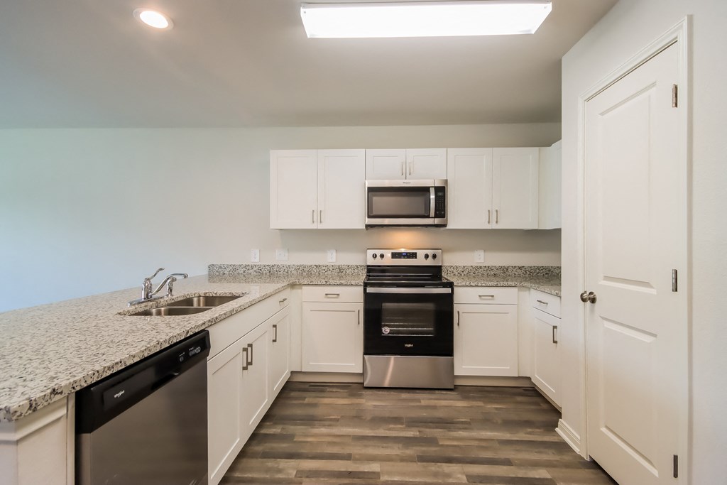a kitchen with white cabinets and granite counter tops and stainless steel appliances