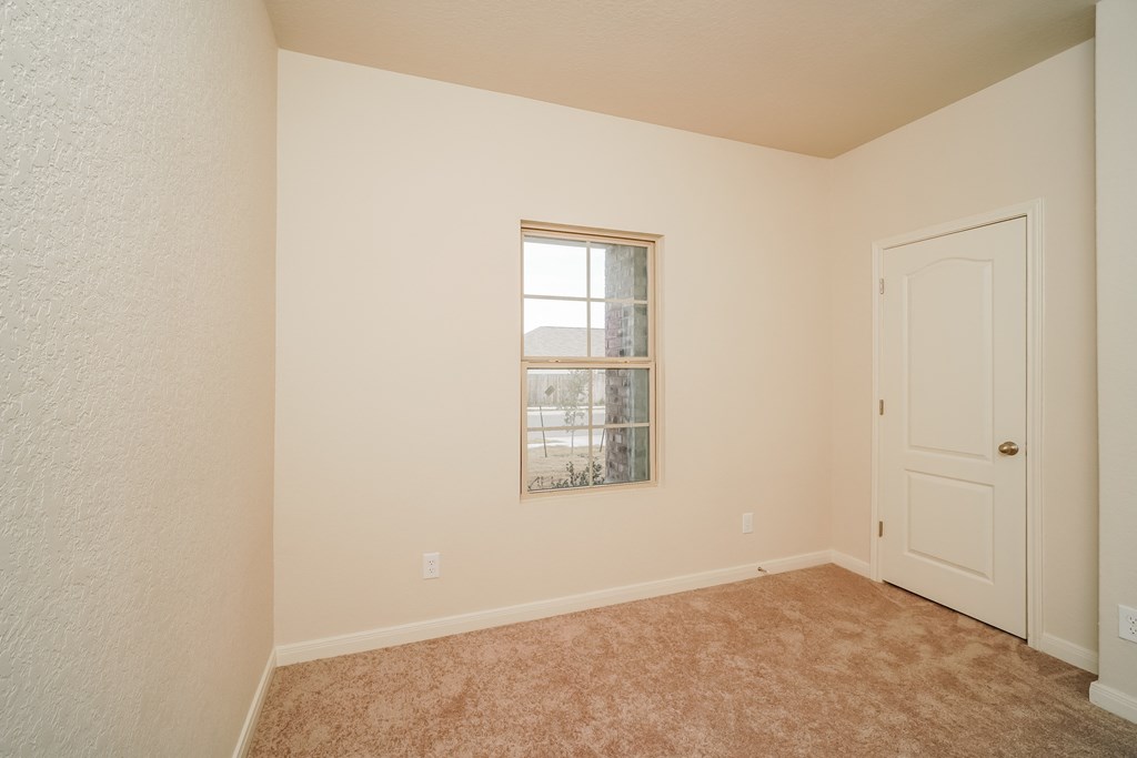 an empty bedroom with a window and a door