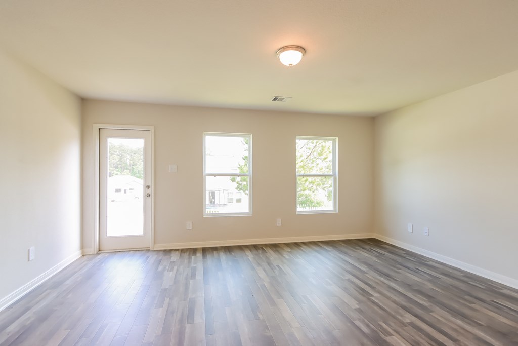 an empty living room with wood floors and windows