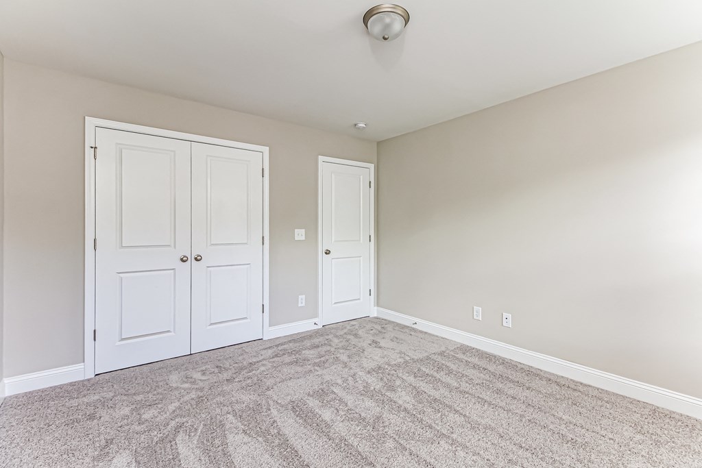an empty bedroom with two doors and carpeting