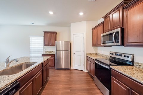 a kitchen with wooden cabinets and granite counter tops and stainless steel appliances