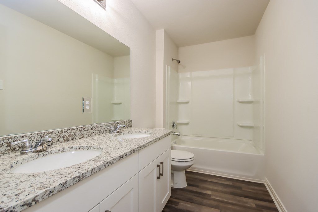 a bathroom with two sinks and a toilet and a shower