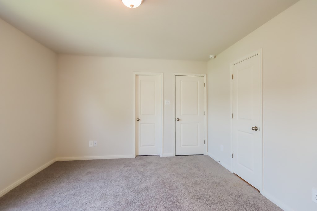 an empty room with two doors and a carpeted floor