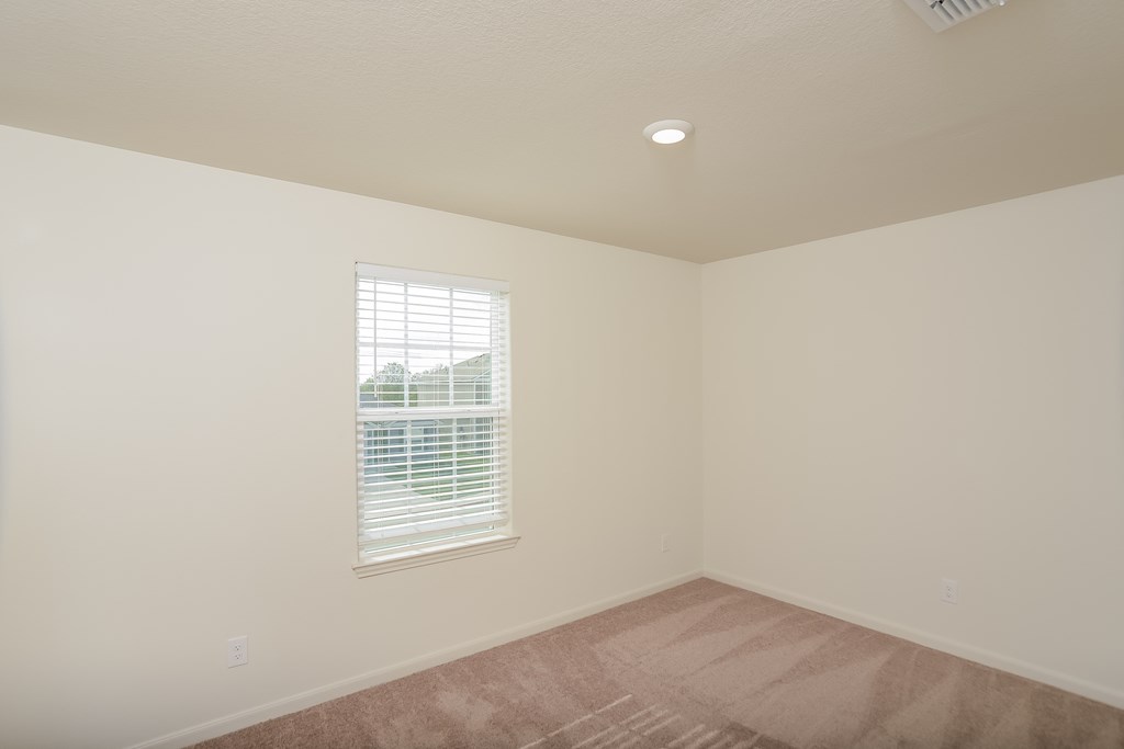 an empty living room with a window and a carpet