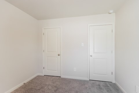 a bedroom with two white doors and a carpeted floor