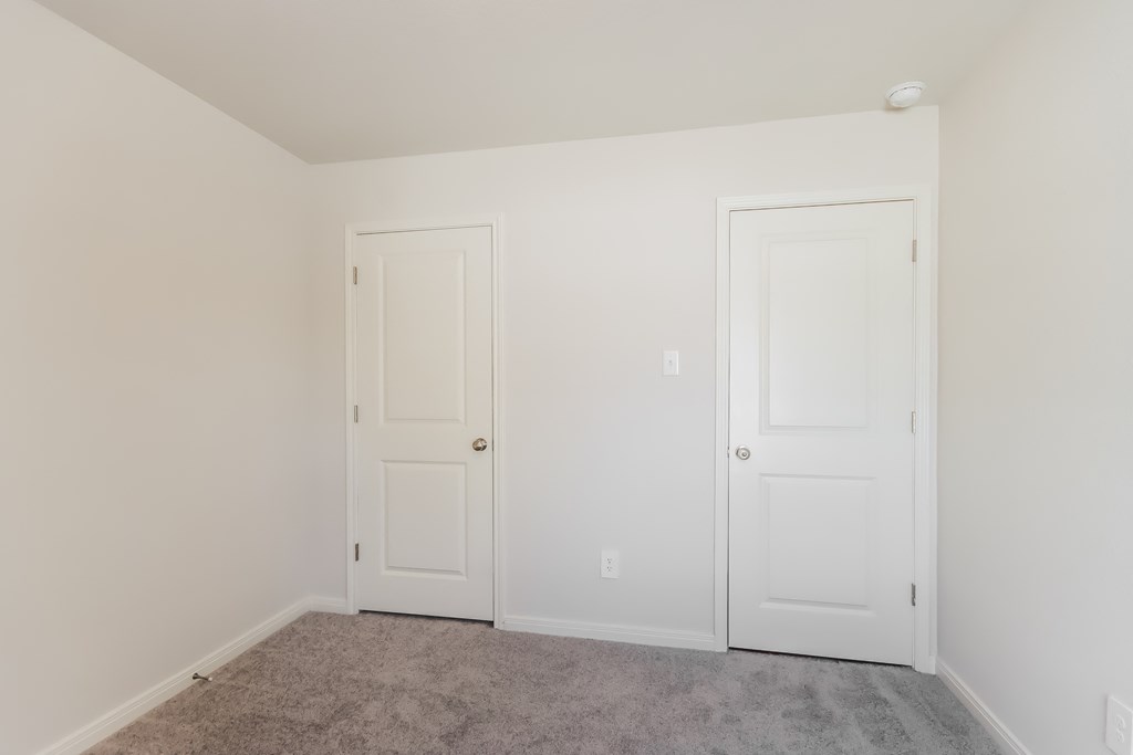 a bedroom with two white doors and a carpeted floor