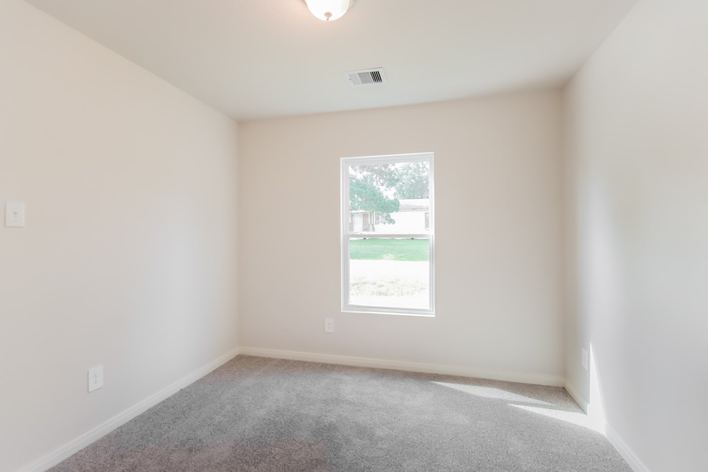 an empty room with a window and carpet