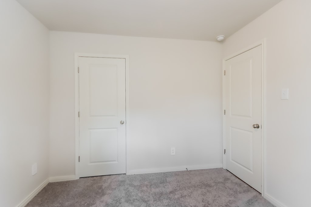 a bedroom with two doors and a carpeted floor