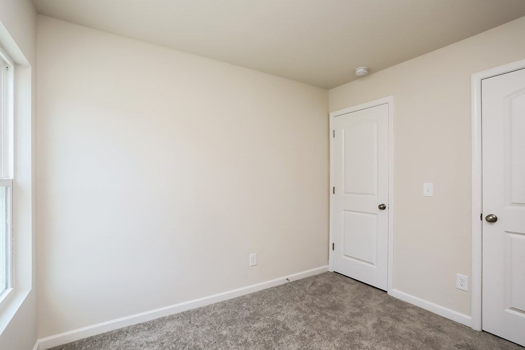 an empty room with two doors and a carpeted floor