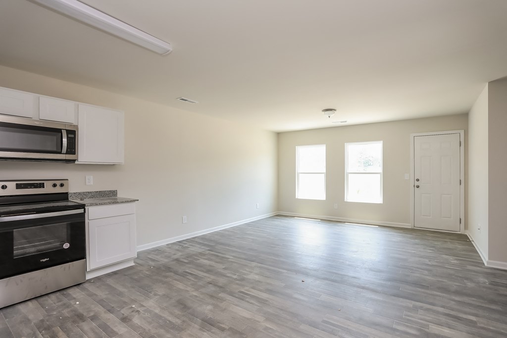 an empty kitchen and living room with a stove and microwave