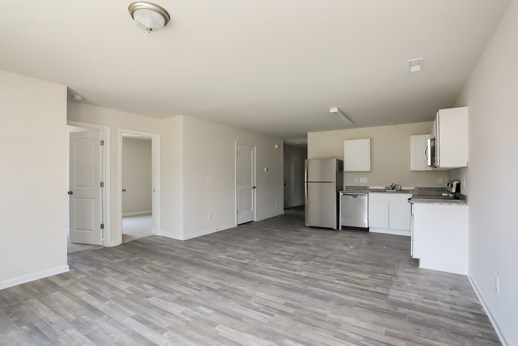 an empty kitchen and living room with white cabinets and stainless steel appliances