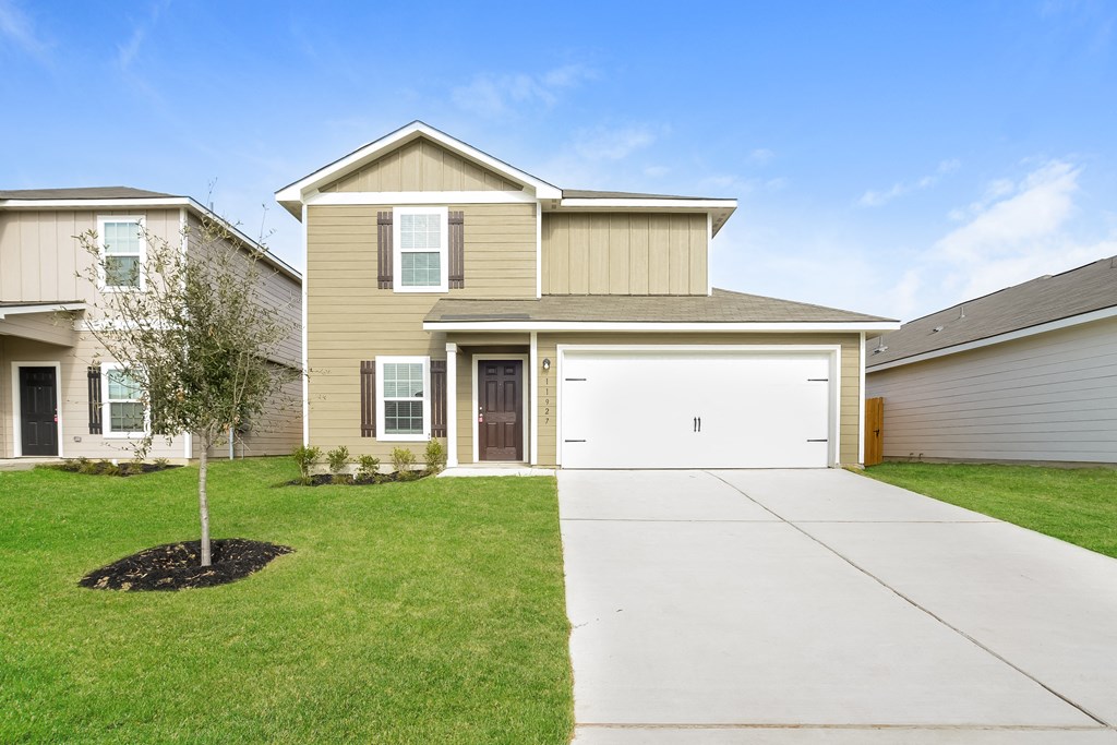 a beige house with a white garage door and a lawn