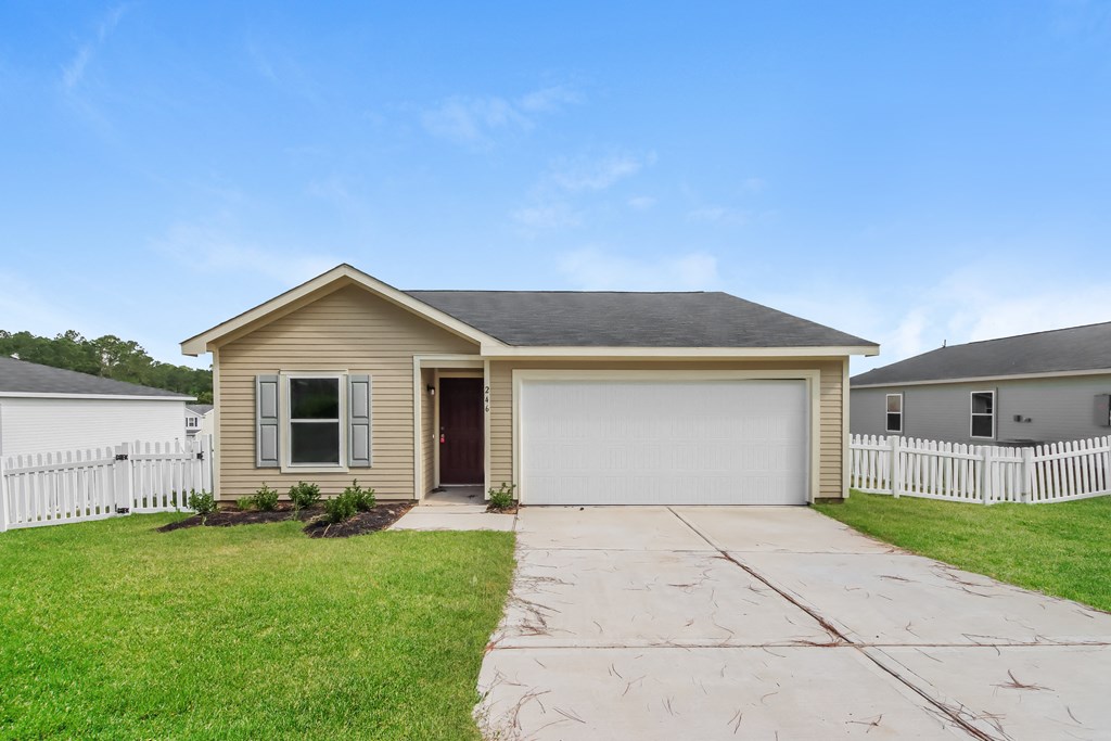 a tan house with a white fence and a driveway