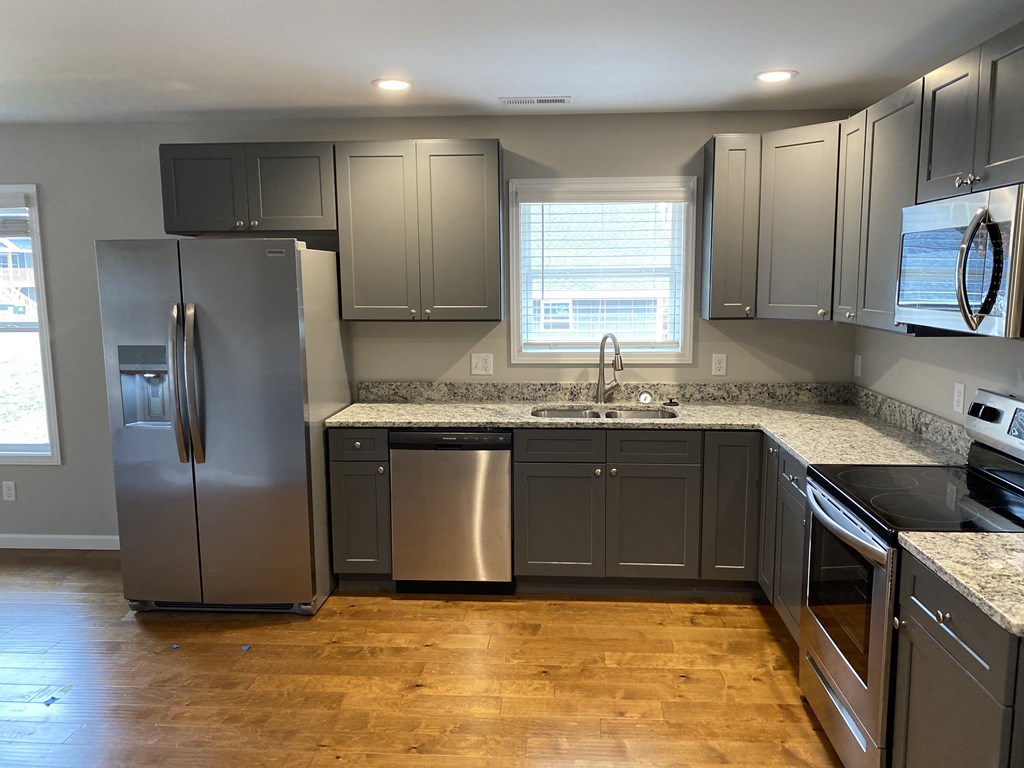 a kitchen with gray cabinets and stainless steel appliances