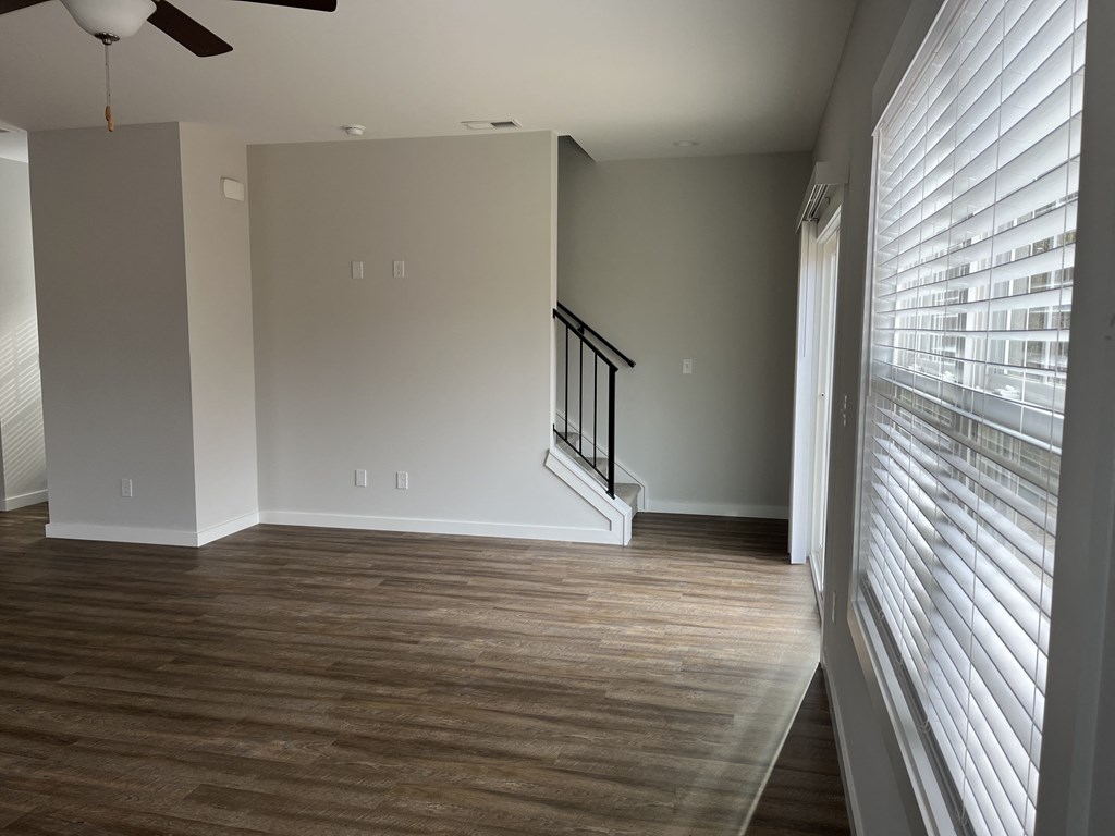 an empty living room with wood flooring and a large window