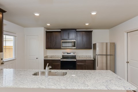 a kitchen with a granite counter top and a stainless steel refrigerator