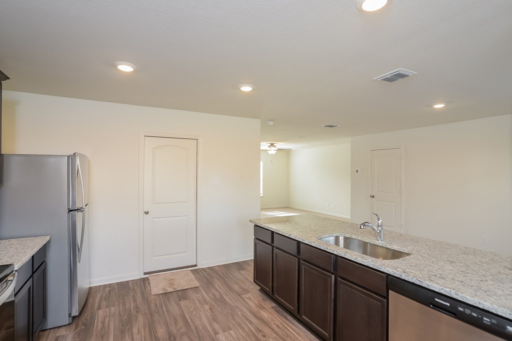 an empty kitchen with a stainless steel refrigerator and sink