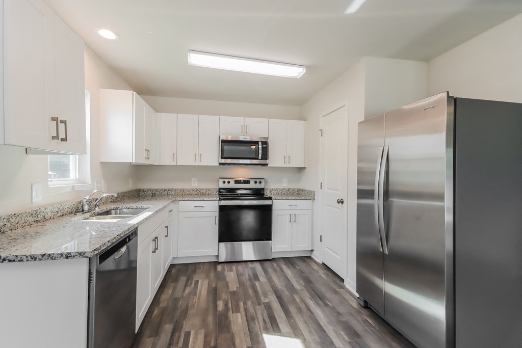 an empty kitchen with white cabinets and stainless steel appliances