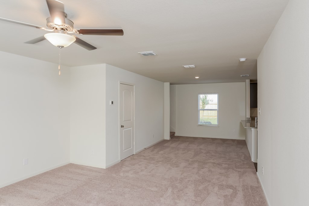 an empty living room with a ceiling fan and white walls