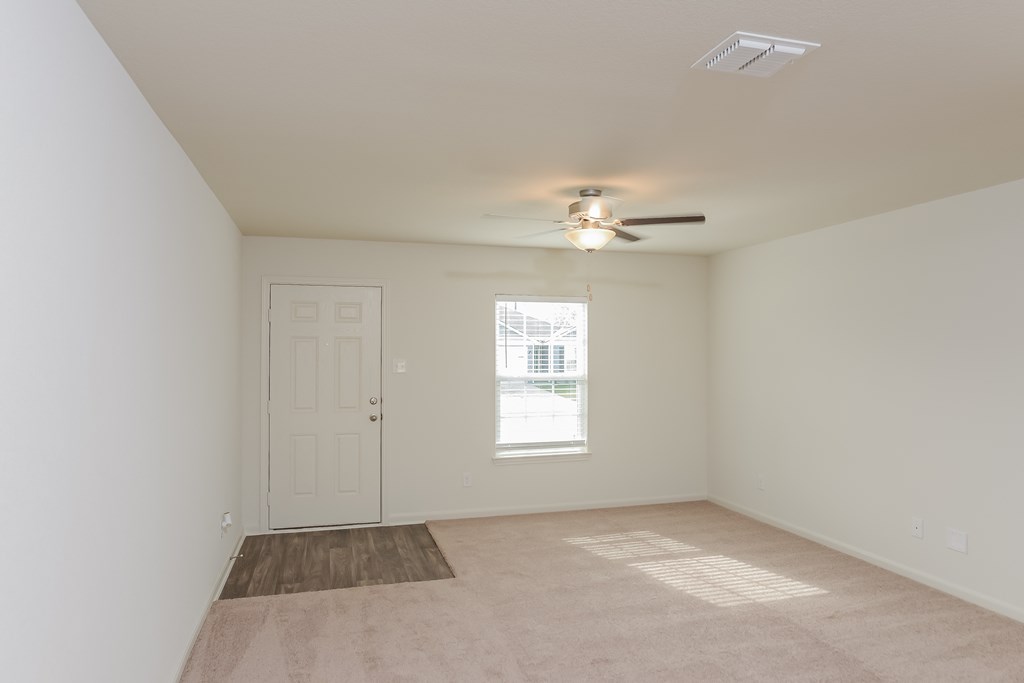 an empty living room with a ceiling fan and a window