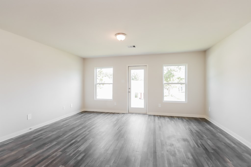 an empty living room with wood floors and white walls