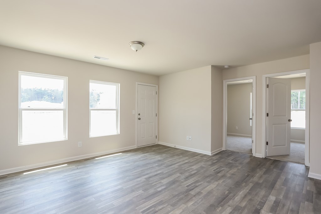 an empty living room with white walls and a wooden floor