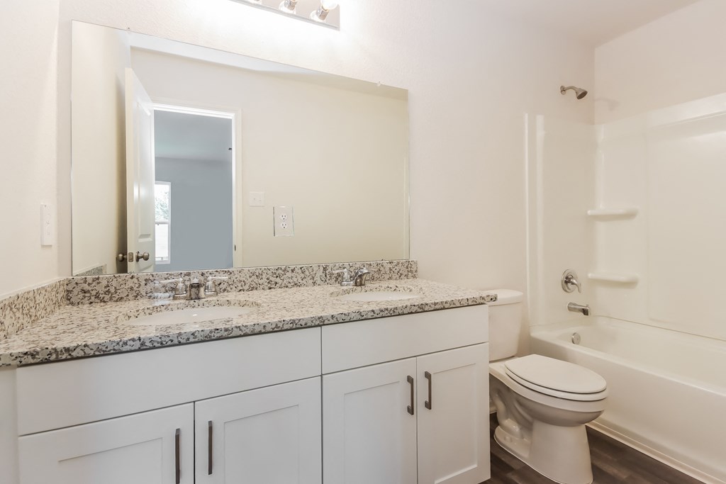 a bathroom with white cabinetry and a large mirror and a white toilet and sink