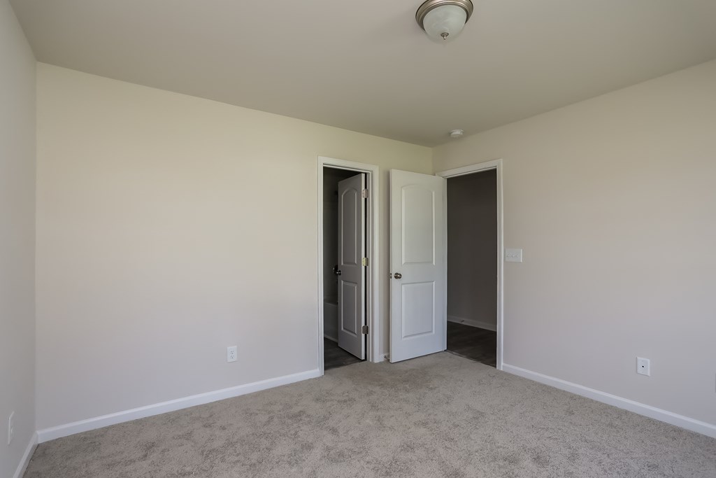 an empty living room with a door to a hallway and a closet