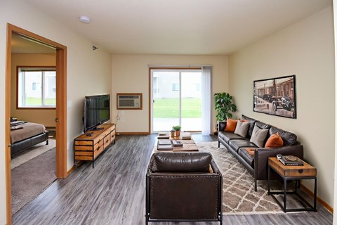 A living room with a brown leather couch and a brown chair.
