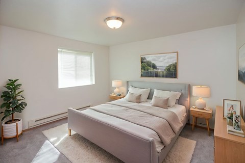 A bedroom with a large bed and a potted plant.