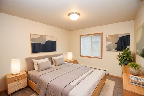 A bedroom with a bed, nightstand, and window.