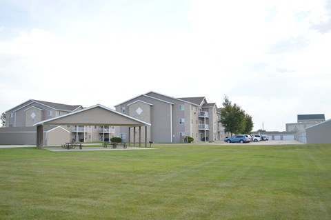 A large grassy field in front of apartment buildings.