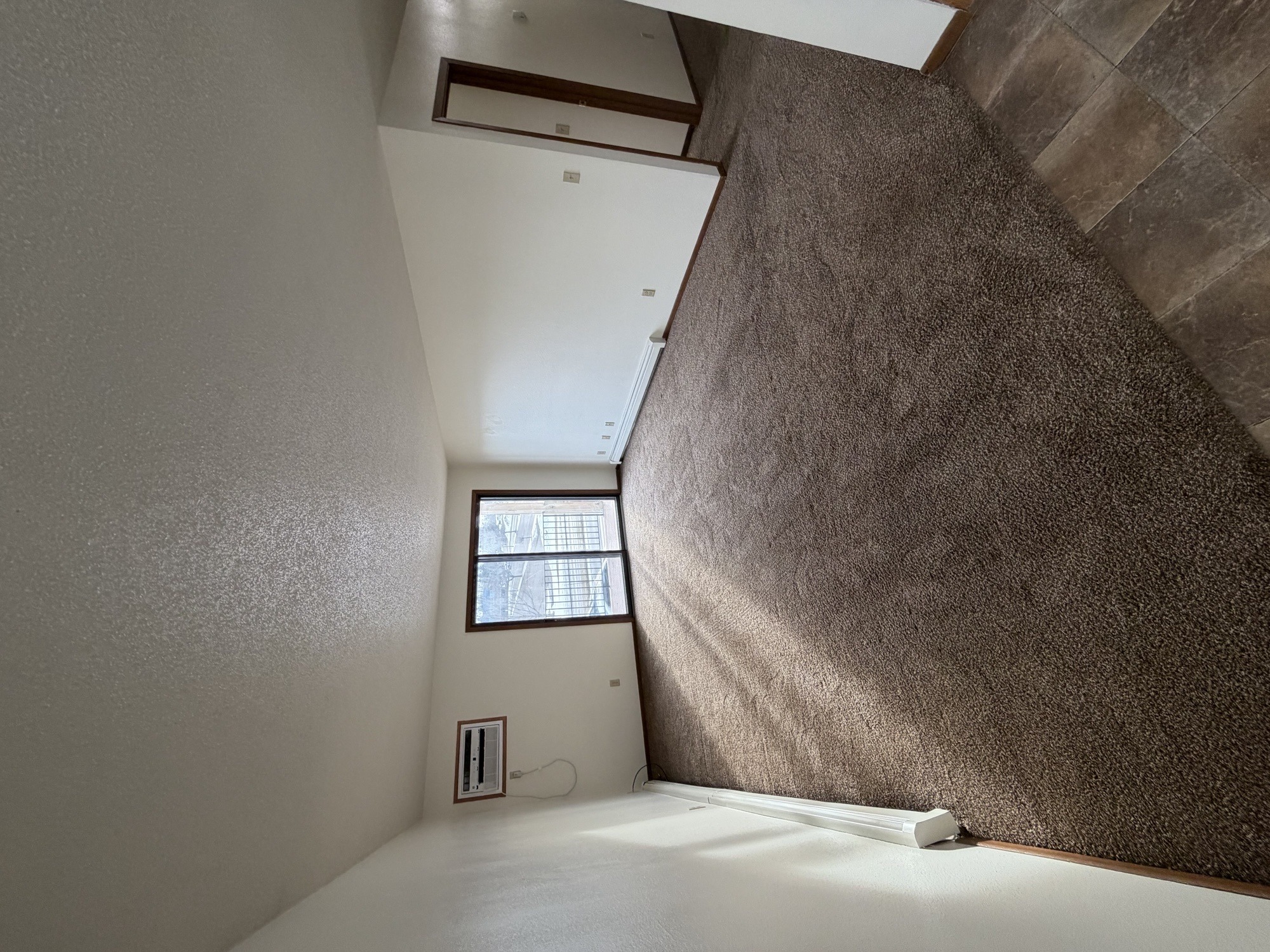 A room with a window and a brown wall.