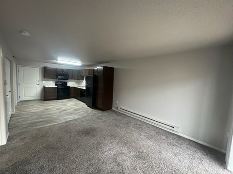 A spacious living room with a grey carpet and white walls.