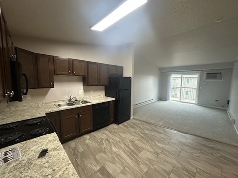 A kitchen with brown cabinets and a black refrigerator.
