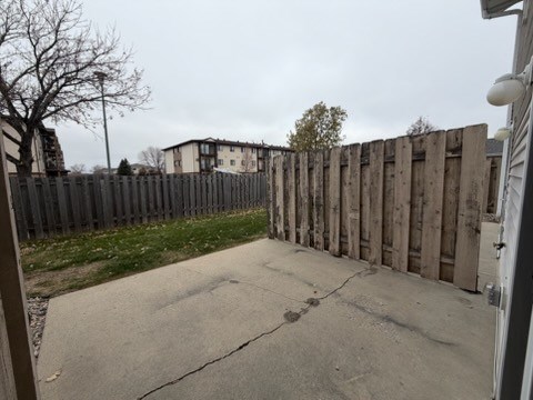 A wooden fence separates a driveway from a grassy area.