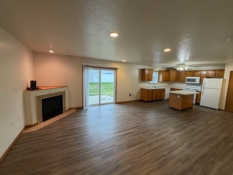 A spacious living room with wood flooring and a fireplace.