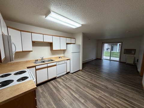 A kitchen with white cabinets and a wooden floor.