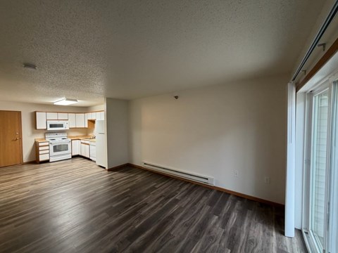 A kitchen with white appliances and wooden floors.