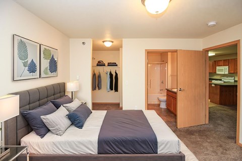 A bedroom with a bed, a lamp, and a coat rack.