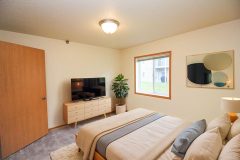 A bedroom with a large bed and a flat screen TV mounted on the wall.