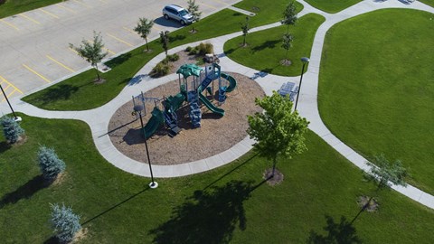 A playground with a green slide and a white fence.