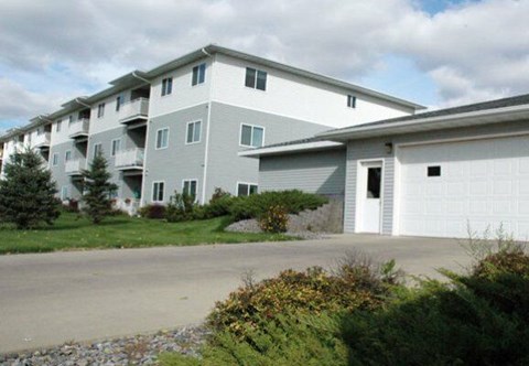 Apartment building with a grey and white exterior and a garage door.