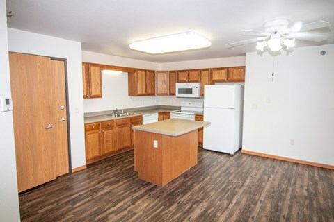 A kitchen with wooden floors and white appliances.