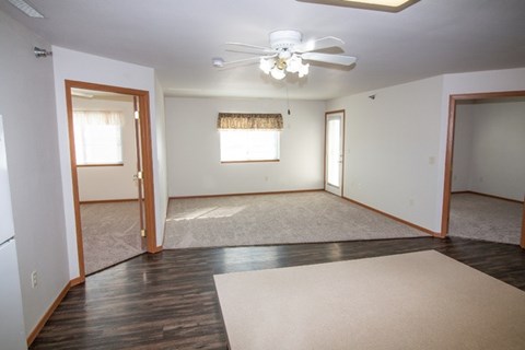 A room with a ceiling fan and a rug on the floor.