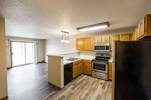 A kitchen with wooden cabinets and a black refrigerator.