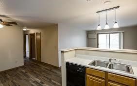 A kitchen with a black dishwasher and wooden cabinets.