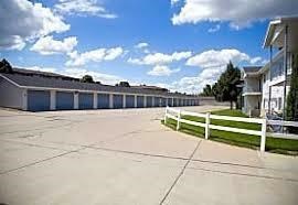 A parking lot with a white fence and a building in the background.